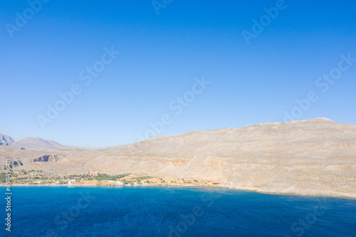 The sandy beach at the foot of the arid mountains , in Europe, Greece, Crete, Kato Zakros, By the Mediterranean Sea, in summer, on a sunny day. photo