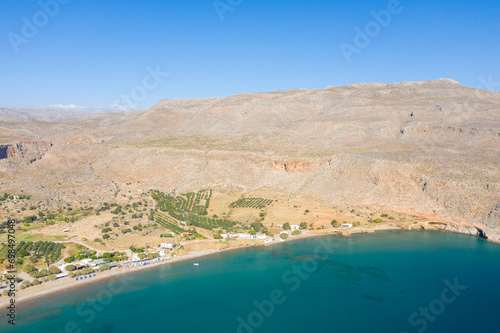 The sandy beach at the foot of the arid mountains , in Europe, Greece, Crete, Kato Zakros, By the Mediterranean Sea, in summer, on a sunny day.