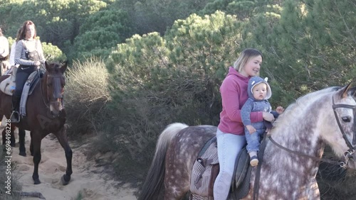 woman with baby and happy friends riding horses in the countryside