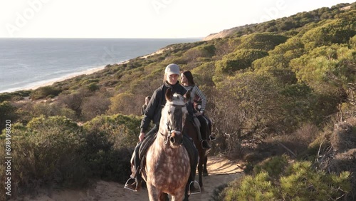 young women riding horses near the sea