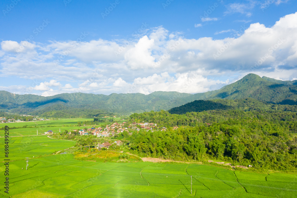 A traditional village by a lake and flooded rice fields in the middle of the mountains, Asia, Vietnam, Tonkin, Dien Bien Phu, in summer, on a sunny day.