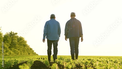 Agriculture. two male farmers walk through farmer field sunset. business meeting two entrepreneurs. two agronomists sunset. team farmers agronomists discuss harvest. organic vegetables. fresh sprouts photo