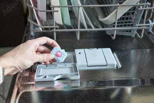 Closeup of woman putting dishwasher detergent into dishwasher machine