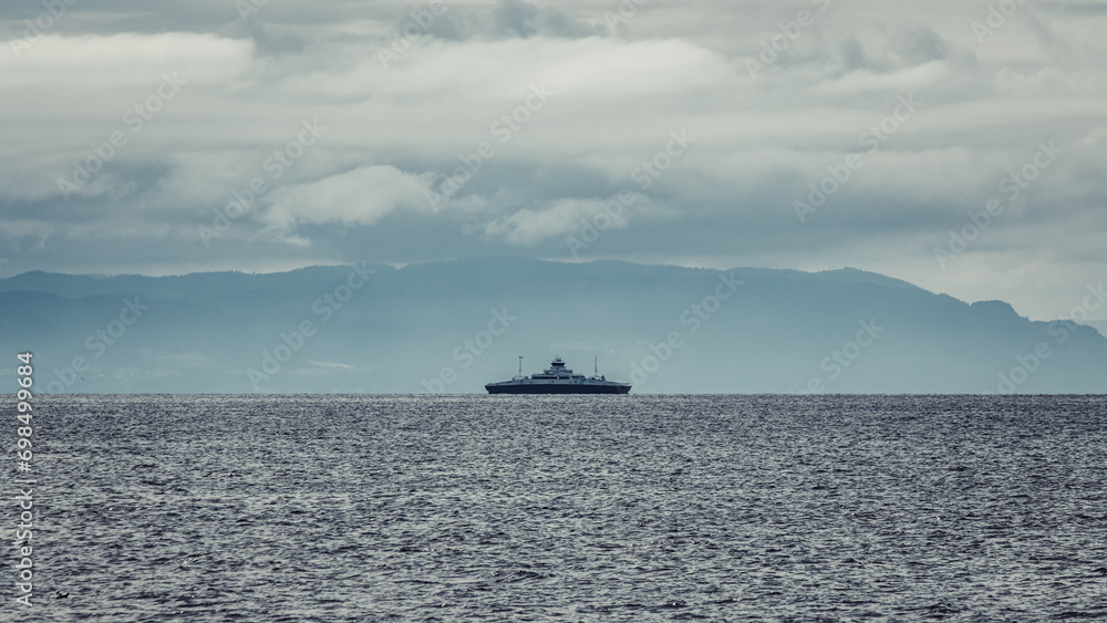 A ferry sailing on the Trondheim Fjord. Dramatic clouds before storm and mountains. A ferry sailing on the Trondheim Fjord. Dramatic clouds before storm and mountains.