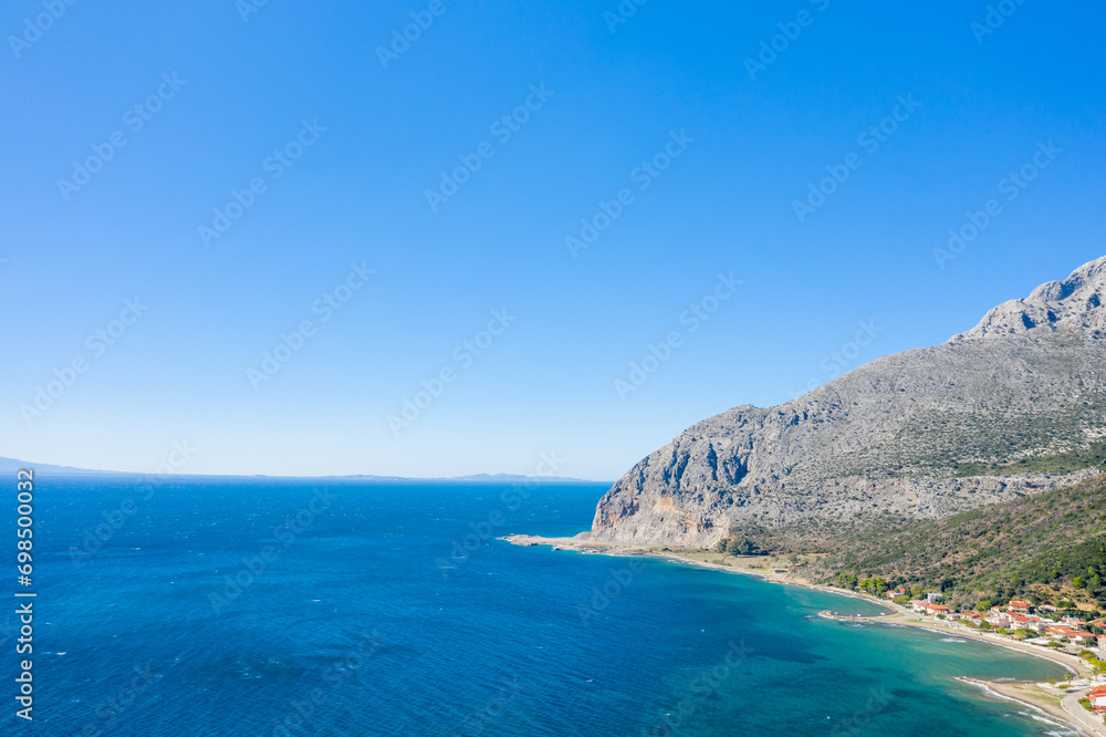 The arid rocky coast and its green countryside, in Europe, in Greece, in Aetolia Acarnania, towards Patras, by the Ionian Sea, in summer, on a sunny day.