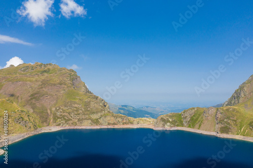 The blue lake in the green countryside in the mountains , Europe, France, Occitanie, Hautes-Pyrenees, in summer on a sunny day.