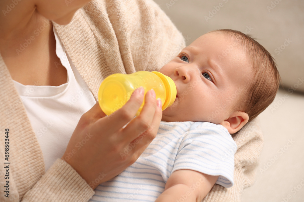 Mother feeding her cute child with infant formula indoors Mother feeding her cute child with infant formula indoors