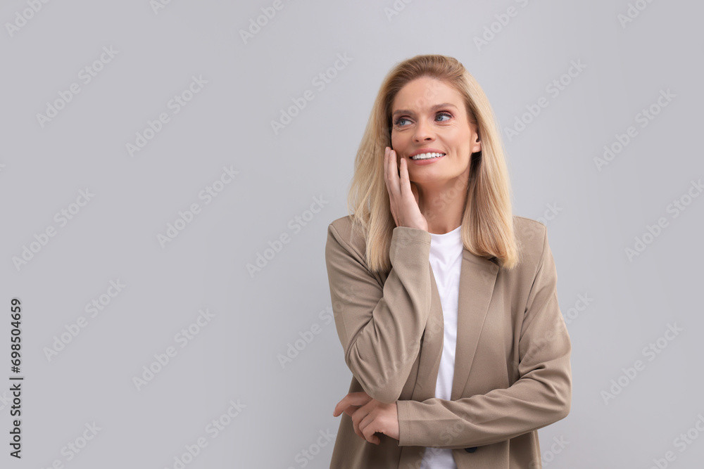 Portrait of smiling middle aged businesswoman on light grey background. Space for text