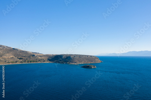 The arid rocky coast and its green countryside along small beaches, in Europe, Greece, Peloponnese, Argolis, Nafplio, Myrto seashore, in summer, on a sunny day. © Florent
