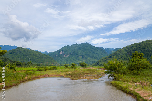 A river in the middle of green rice fields and mountains, in Asia, Vietnam, Tonkin, towards Hanoi, Mai Chau, in summer, on a sunny day.