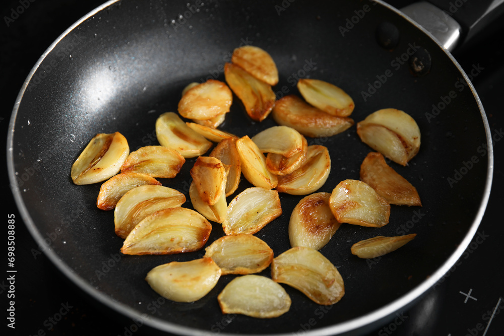 Frying pan with fried garlic cloves, closeup