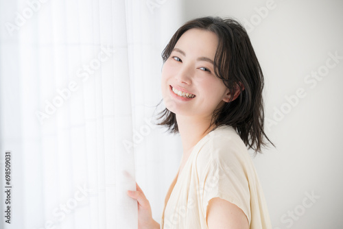 窓辺に佇む若い女性　カメラ目線の笑顔 photo