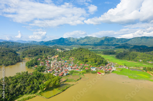 A traditional village by a lake and flooded rice fields in the middle of the mountains, Asia, Vietnam, Tonkin, Dien Bien Phu, in summer, on a sunny day.