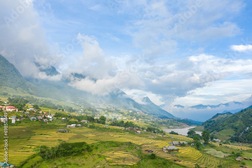 The traditional village with green and yellow rice fields in the green mountains, Asia, Vietnam, Tonkin, Sapa, towards Lao Cai, in summer, on a cloudy day.