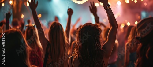 Stylishly dressed girls dancing and raising hands at a modern indoor club concert.