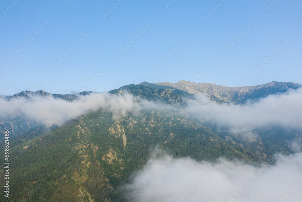 Fototapeta premium The green countryside under the clouds in Europe, France, in the Pyrenees, in summer, on a sunny day.