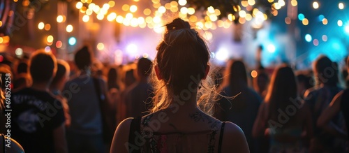 People with black and white silhouettes on their shoulders at a backlit music festival. photo