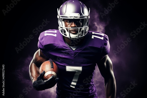 Portrait of American football player running with the ball. Muscular athlete in a purple and yellow uniform with an ovoid ball in a dynamic pose. Isolated on black background.