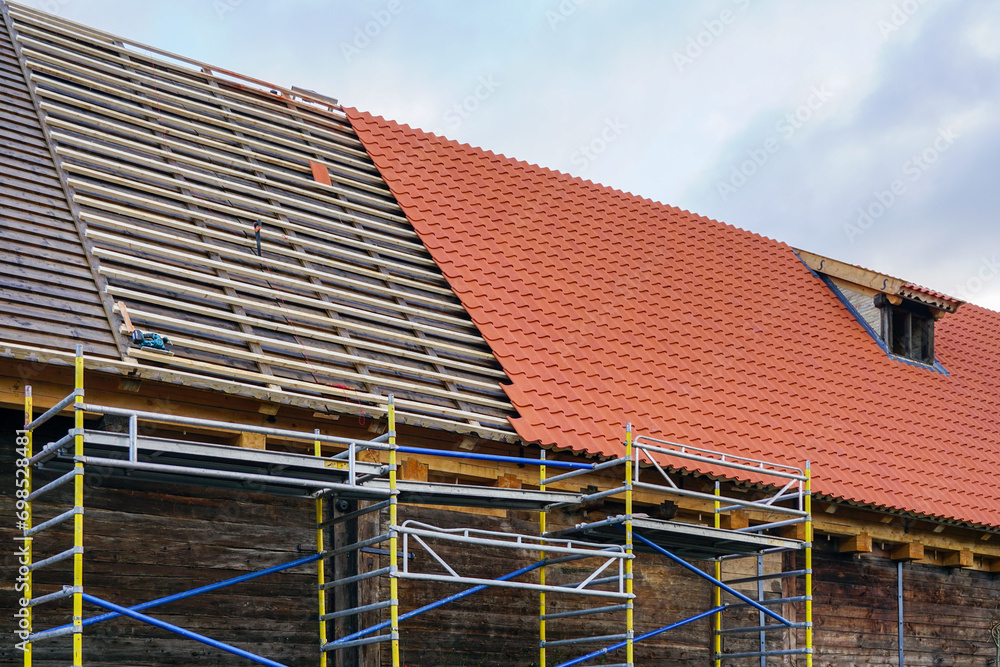 Installation of new clay tiles on new wooden battens on the roof of a historic house Installation of new clay tiles on new wooden battens on the roof of a historic house