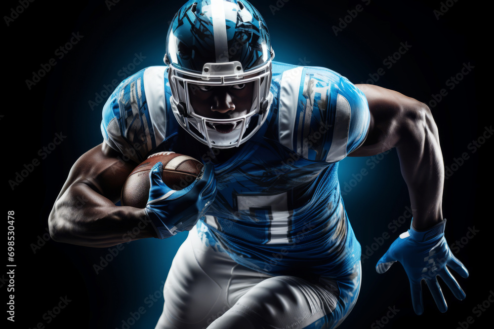 Portrait of American football player running with the ball. Muscular athlete in a blue and white uniform with an ovoid ball in a dynamic pose. Isolated on black background.