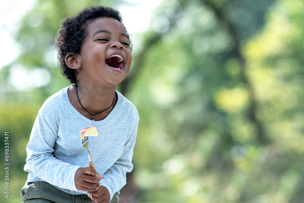 African boy having fun laughing heartily with someone, amidst a bright summer atmosphere at a park African boy having fun laughing heartily with someone, amidst a bright summer atmosphere at a park