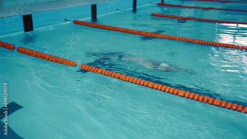 Athlete swimmer man swims, makes a turn under water and continues to swim in the backstroke style. Male swimmer swimming in the indoor pool photo