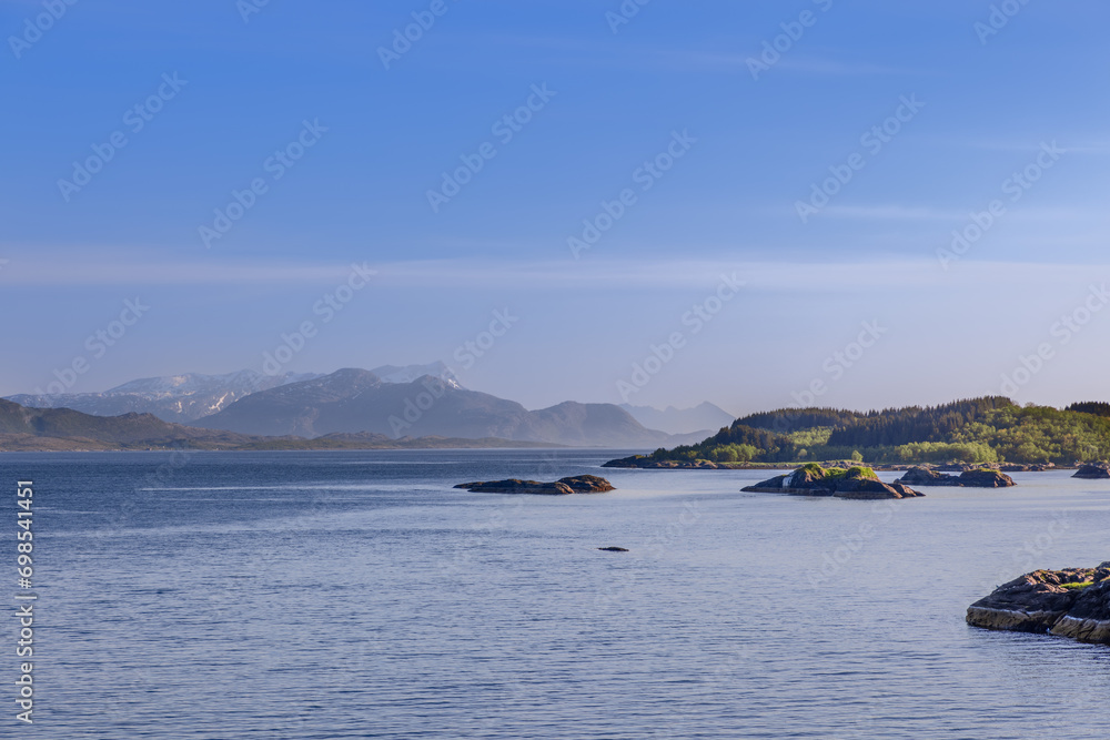 Serene summer day view of the calm waters of Saltfjorden, part of the dramatic Lofoten archipelago, near Bodo, Norway, under a clear blue sky