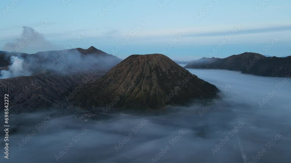 Sunrise drone flight up to active volcano Bromo, East Java, Indonesia, surrounded by mourning clouds Sunrise drone flight up to active volcano Bromo, East Java, Indonesia, surrounded by mourning clouds