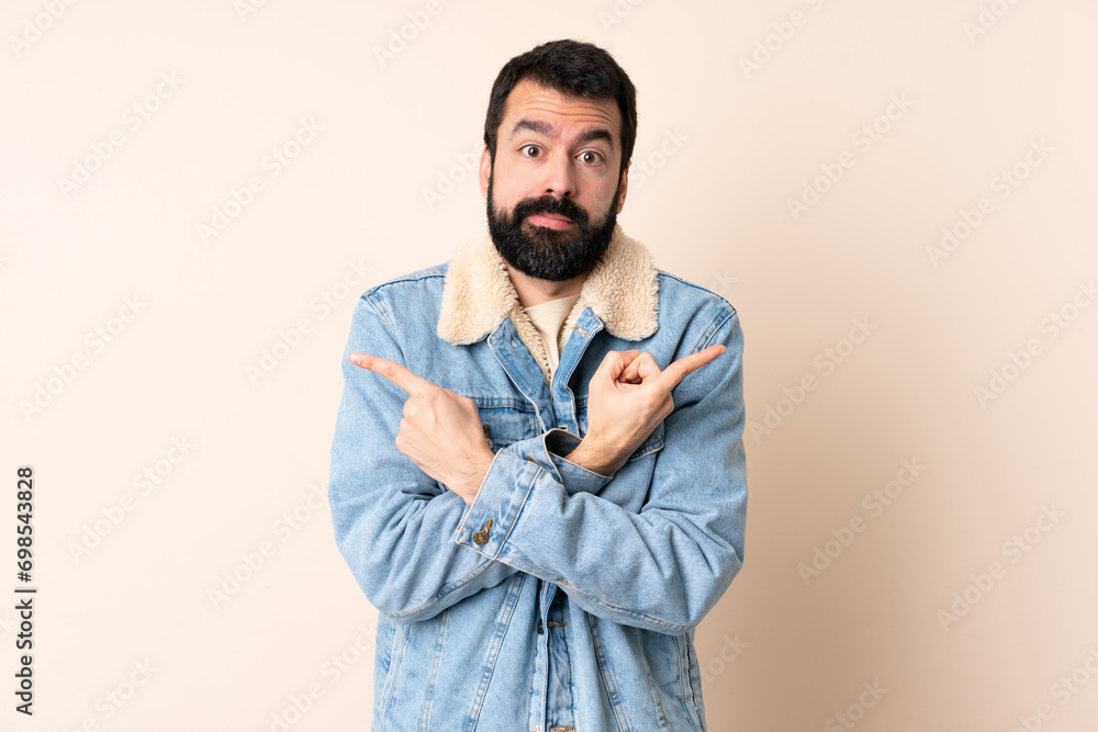 Caucasian man with beard over isolated background pointing to the laterals having doubts Caucasian man with beard over isolated background pointing to the laterals having doubts