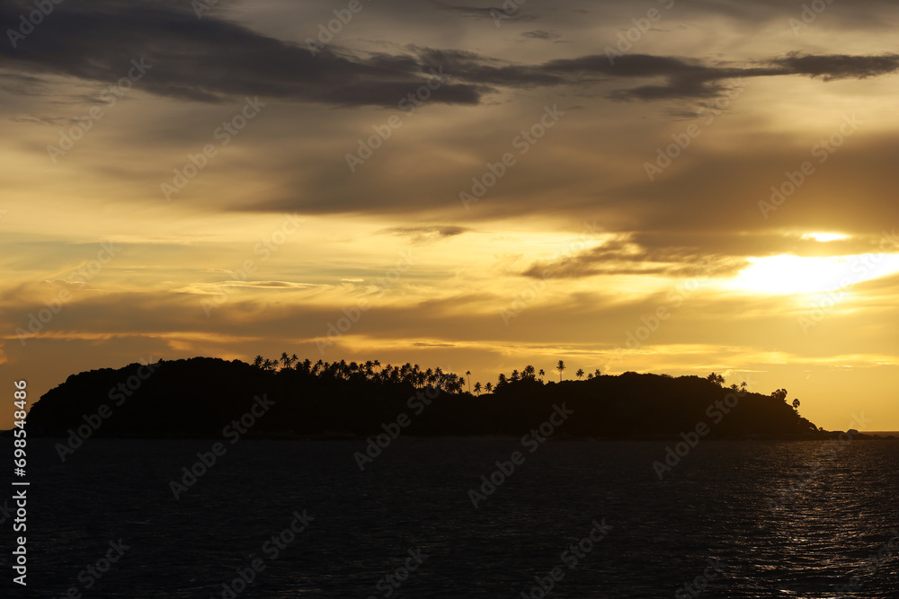 Silhouettes of coconut palm trees on tropical island at sunset, background for sea vacation and travel