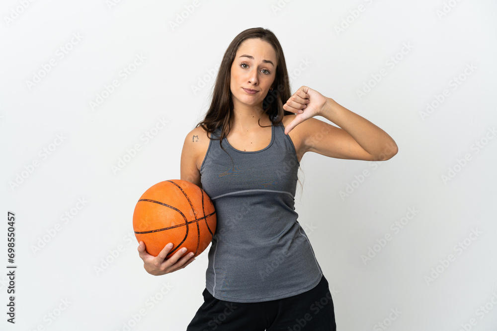 Young woman playing basketball over isolated white background showing thumb down with negative expression