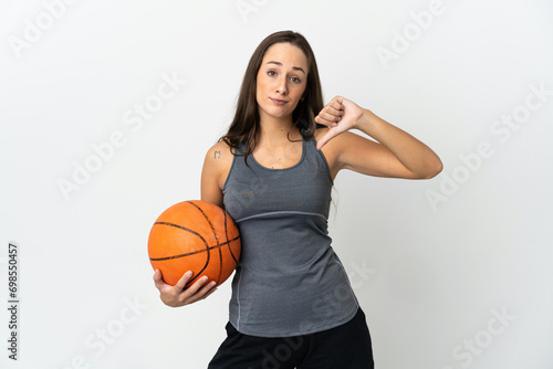 Young woman playing basketball over isolated white background showing thumb down with negative expression