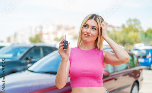 Young pretty blonde woman holding car keys at outdoors having doubts and with confuse face expression © luismolinero