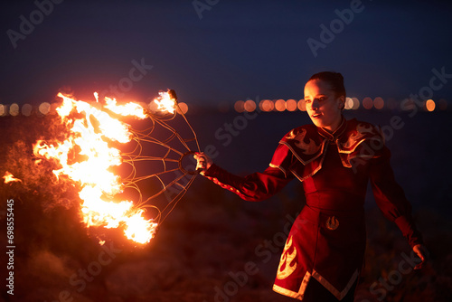 Waist up portrait of female performer dancing with fire fans outdoors at night, copy space photo