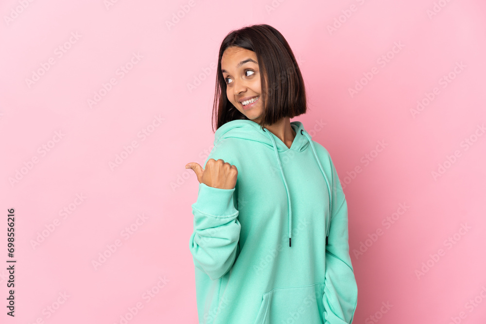 Young latin woman isolated on pink background pointing to the side to present a product Young latin woman isolated on pink background pointing to the side to present a product