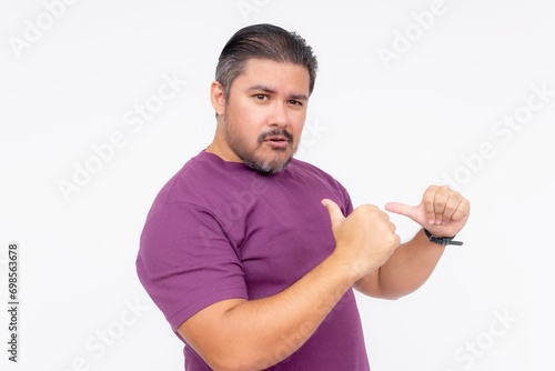A cocky man points to himself with his thumbs, bragging while looking smug - but looking funny. Wearing a purple waffle shirt. Half body photo isolated on white background. photo