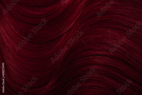 Dark red hair close-up as a background. Women s long brown hair. Beautifully styled wavy shiny curls. Coloring hair with bright shades. Hairdressing procedures  extension.