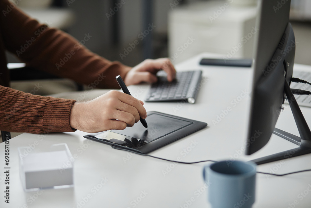 Close up of unrecognizable man using pen tablet for editing photos or videos at desk in office, copy space Close up of unrecognizable man using pen tablet for editing photos or videos at desk in office, copy space