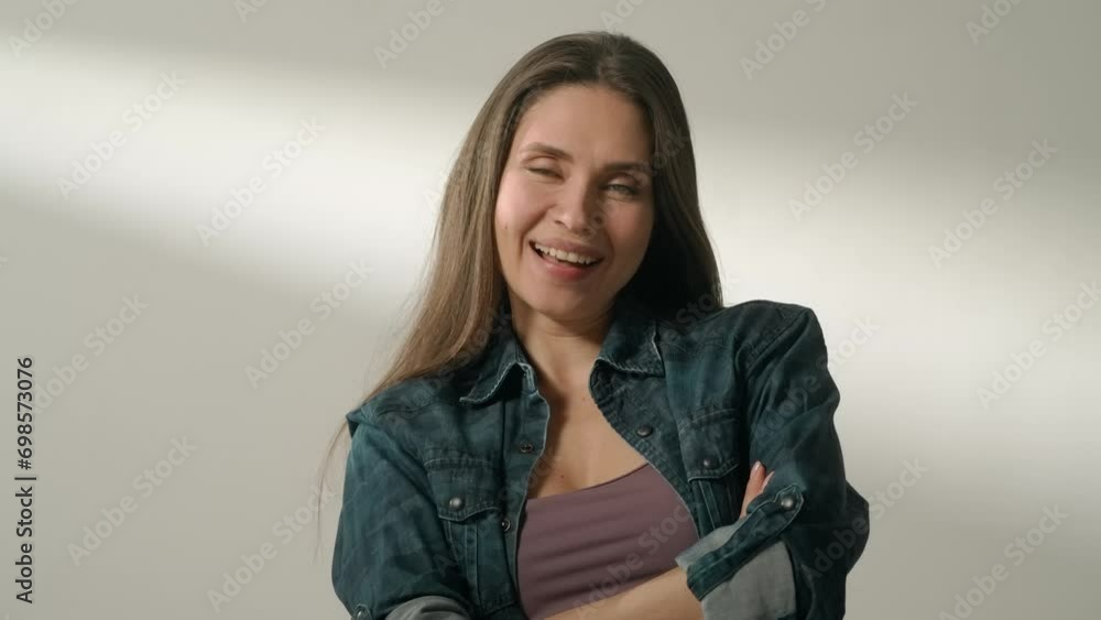 Portrait of attractive female model in positive mood. Brunette woman in casual clothing sitting in the studio and laughing with crossed hands. Portrait of attractive female model in positive mood. Brunette woman in casual clothing sitting in the studio and laughing with crossed hands.