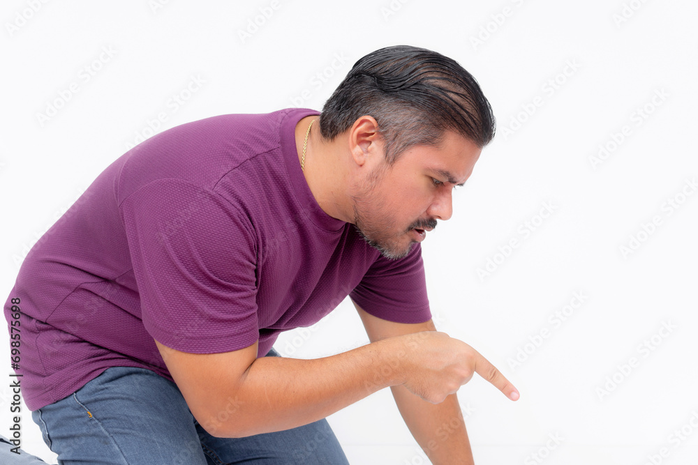 A curious man kneeling and bending down, looking and pointing at something on the ground. Isolated on a white background.