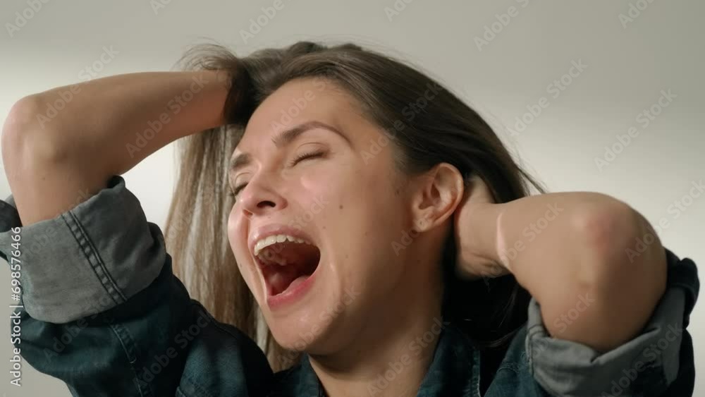 Portrait of attractive female model in positive mood. Brunette woman in casual clothing sitting in the studio holding head and laughing loud.