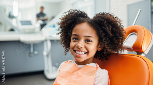 A smiling african american kid sitting in a dental chair at the dentist, teeth cleaning and examination concept, beautiful white teeth smile, young girl checkup photo
