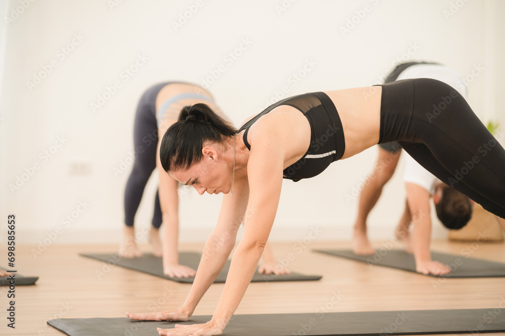 Fototapeta premium Happy yoga instructor enjoying while teaching a group class to young people in studio