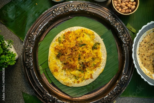 South Indian Food Uttapam on banana leaf in copper plate, oothappam copper plate over banna leaf, Dosa platter, Savoring South Indian Delights, South Indian breakfast dish. photo