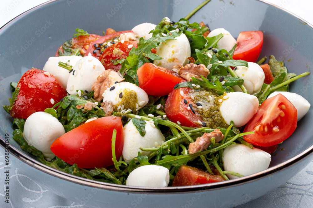 Caprese salad, cherry tomatoes, mozzarella, arugula and pesto sauce. Isolated image Caprese salad, cherry tomatoes, mozzarella, arugula and pesto sauce. Isolated image
