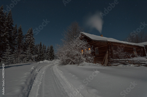 a village house near a snowy road smoke from a chimney forest