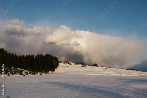 Big clouds over a village house on a hill on a winter evening