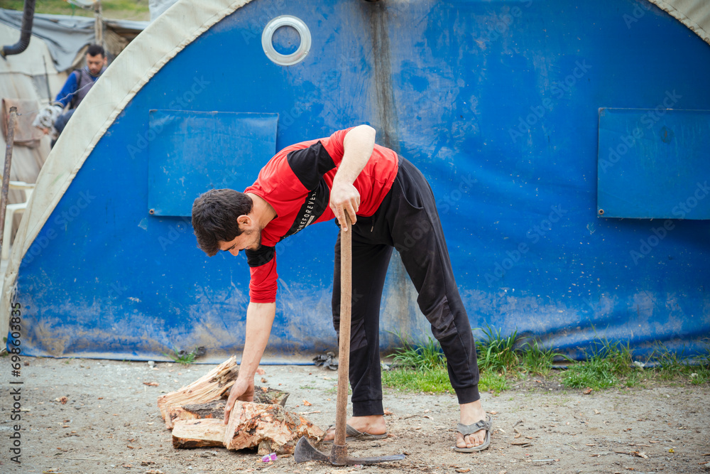 A refugee man breaks firewood in order to use it for cooking and heating. The suffering of Syrian refugees A refugee man breaks firewood in order to use it for cooking and heating. The suffering of Syrian refugees