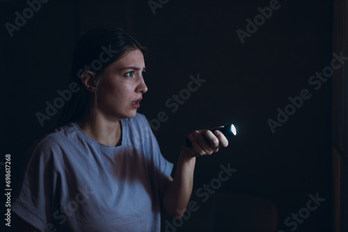 Woman scared holding hand flashlight in darkness and afraid of violence criminal robbery