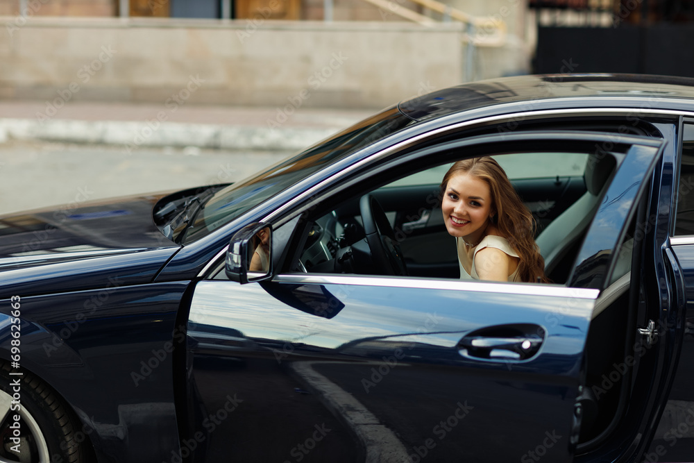 Happy woman driver entering car smiling. Cute young happy brunette female driving car vehicle